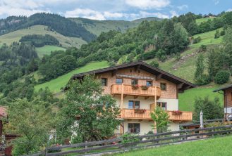 Haus Obersamer im Raurisertal mit Balkon und Bergblick, umgeben von grünen Wiesen und Wäldern.