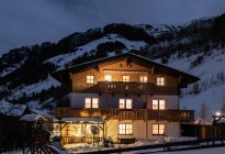 Haus Obersamer im Raurisertal, abends beleuchtet, im Winter mit Bergen im Hintergrund.